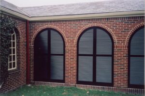 Arched exterior fixed louvered shutters for porch breezeway